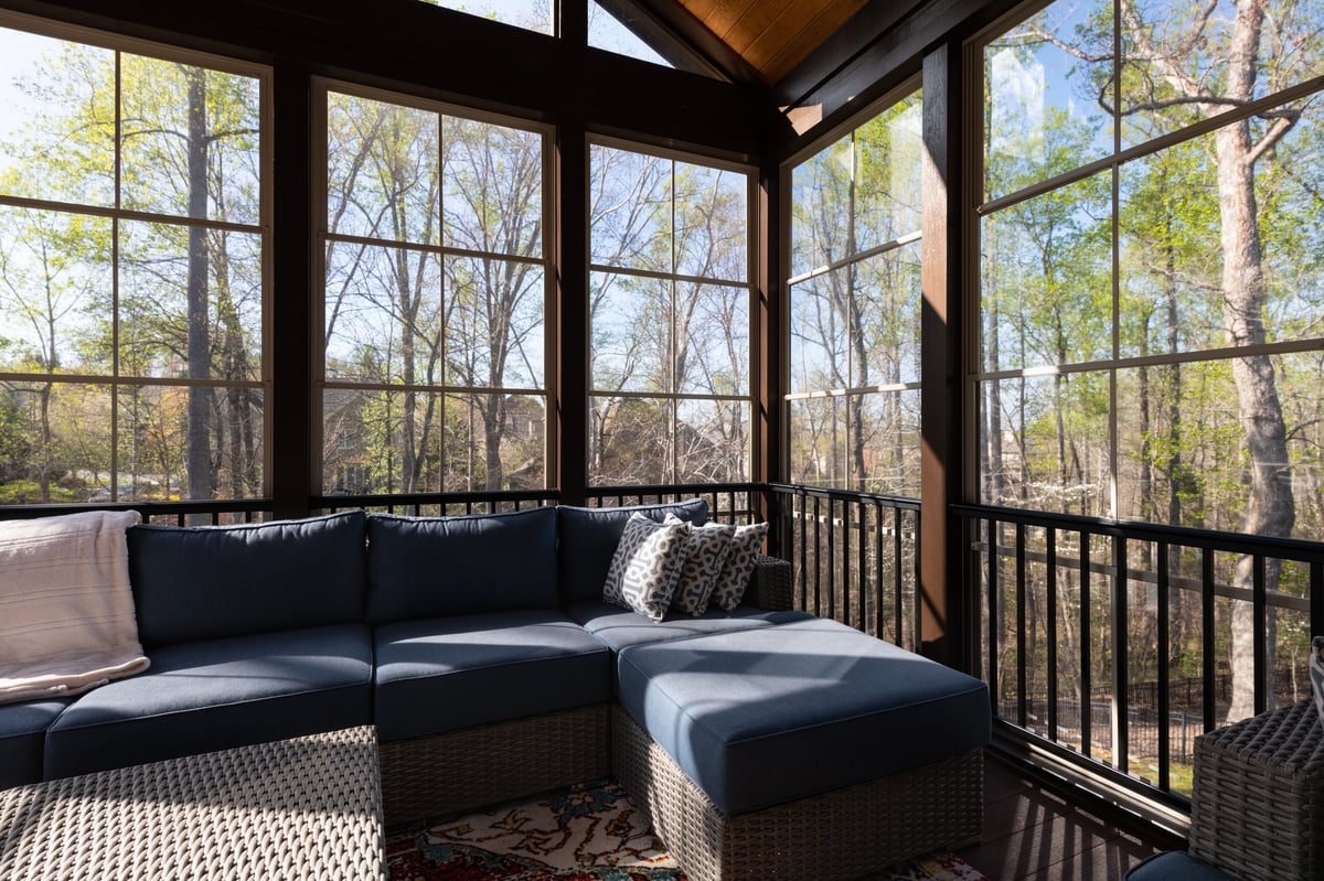 Modern screened porch in springtime, full of blooms trees in the background.