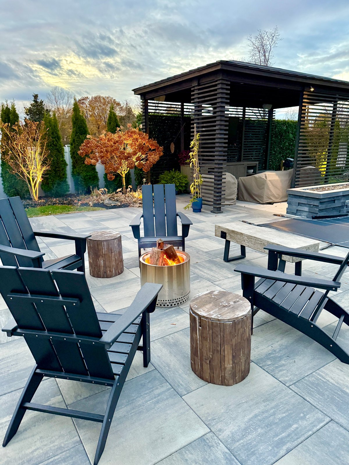 Outdoor backyard entertaining space with firepit, seating, and beautiful landscaping