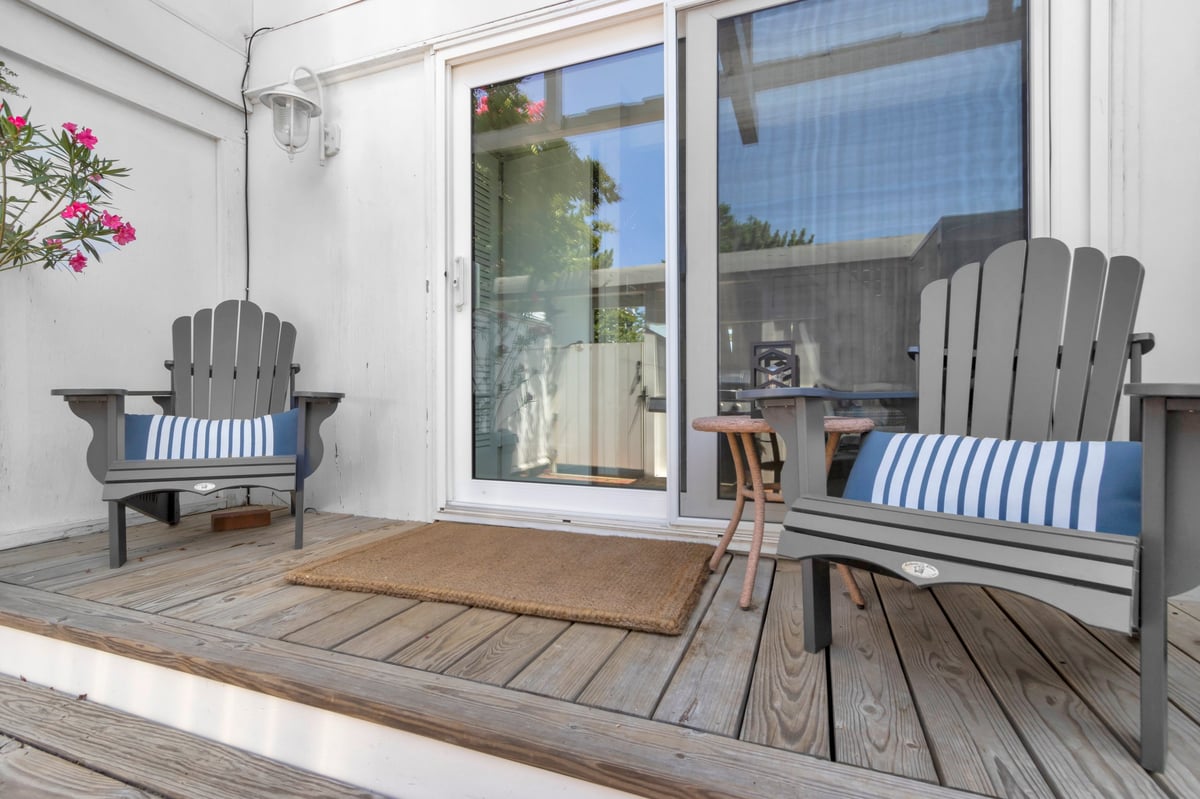 A pair of adirondack chairs sit on either side of a sliding glass door to welcome anyone coming to the door