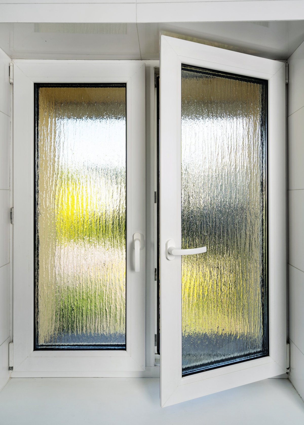 Open window with blurred glass in bathroom, modern PVC frame featuring double insulated panes for comfort in residential interior