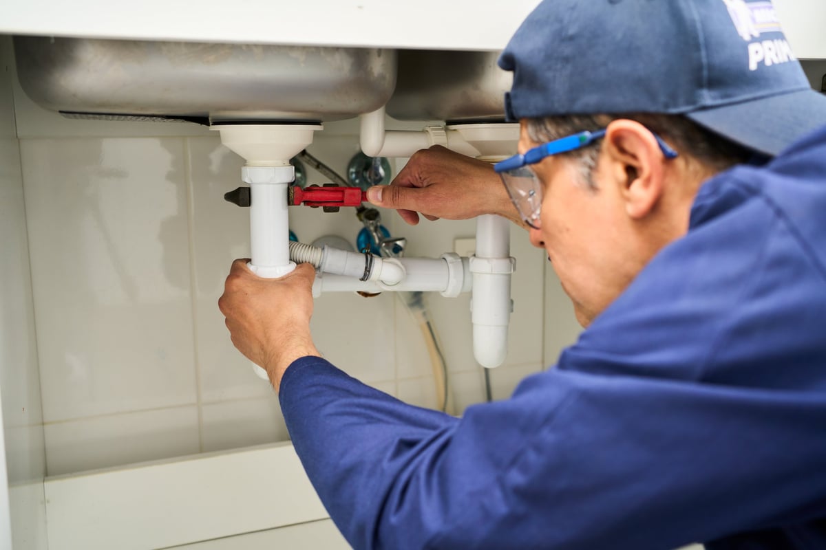 Plumber repairing sink in kitchen
