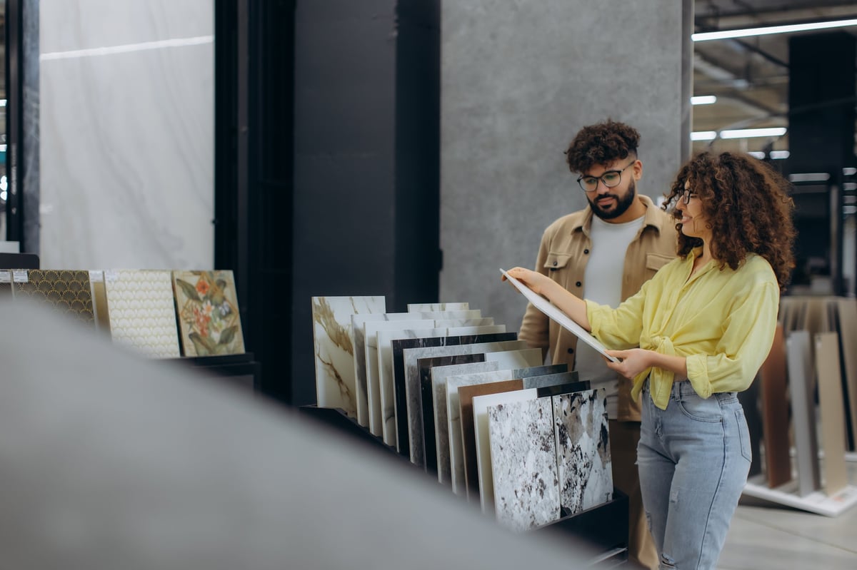 Young couple selecting ceramic floor or wall tiles in a showroom, planning interior design for their new house project