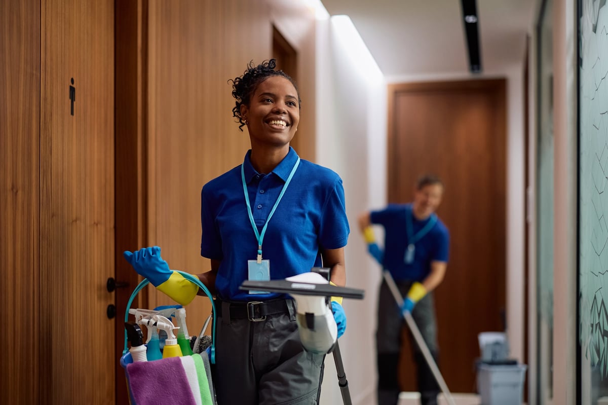 Happy professional with cleaning supplies in office building