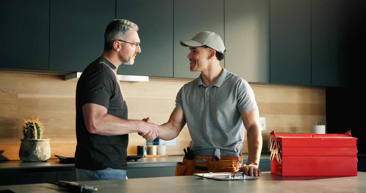 Men, plumber and client with handshake in kitchen for solution, maintenance and leak repair. Homeowner, handyman and shaking hands in home for help, job completion and thank you for call out service