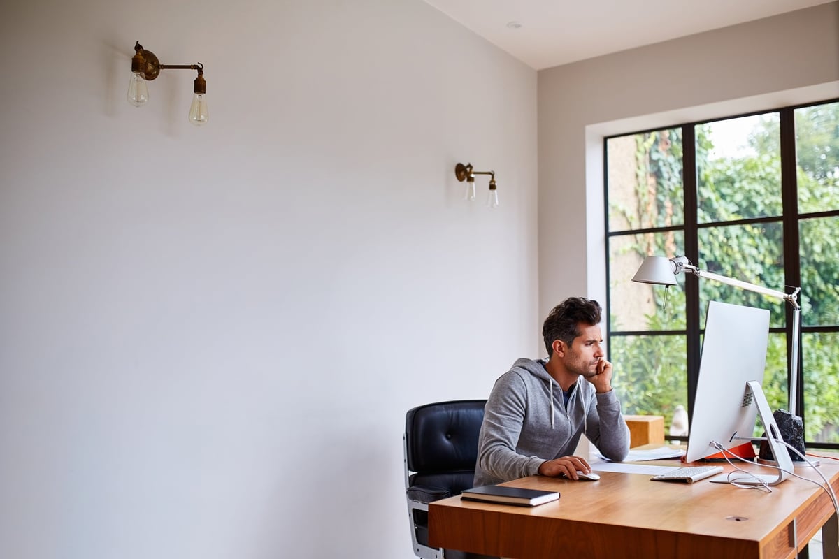 Shot of a young man working on a computer while sitting at a desk in his home office