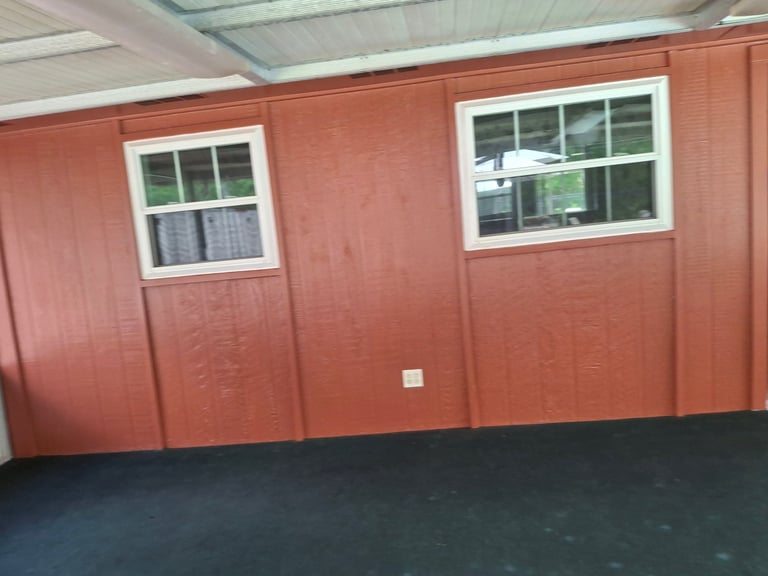 Interior of a red metal storage building with white-framed windows and dark flooring