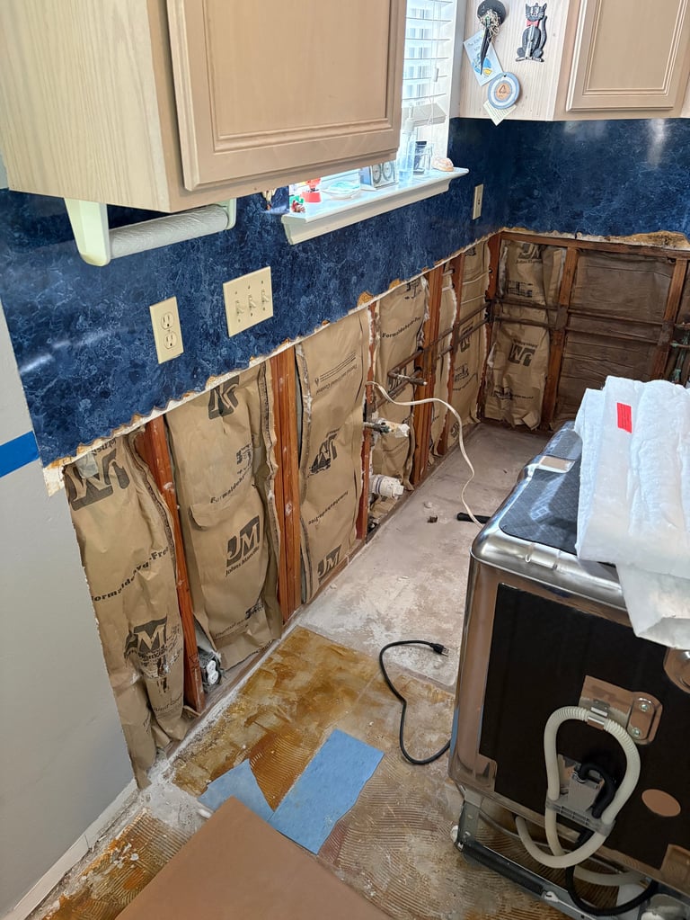 Kitchen under renovation with blue granite countertop, removed cabinet doors, and construction materials on floor