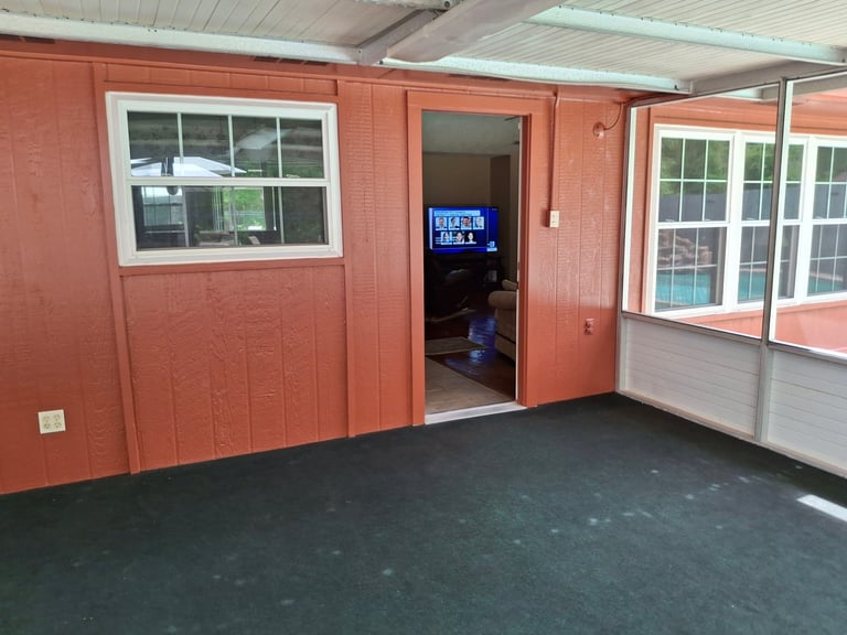 Interior of a red metal building with windows, an open doorway, and dark flooring