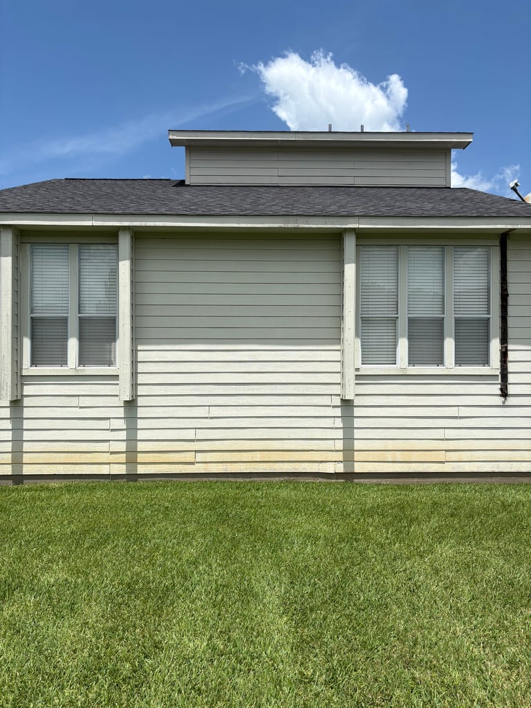 Front view of a modern single-story house with white siding, covered porch, and green lawn under blue sky