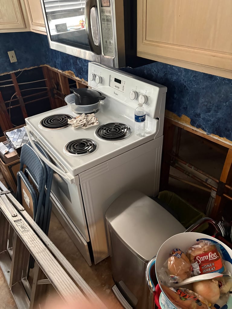 White electric stove with four coil burners in a kitchen with blue tile backsplash and cream cabinets